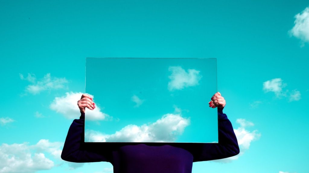 Osoba držící sklenici s jednosměrnou zrcadlovou fólií